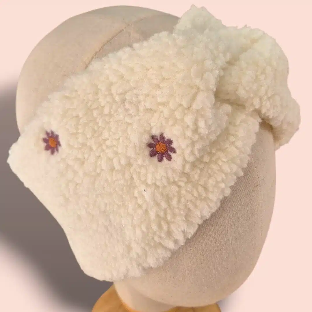 Bandeau en sherpa écru ultra-doux avec pâquerettes brodées, chaud et confortable. L’accessoire d’hiver idéal pour garder vos oreilles au chaud avec style. Un bandeau confortable et élégant, fabriqué à la main sur l’Île d’Oléron.